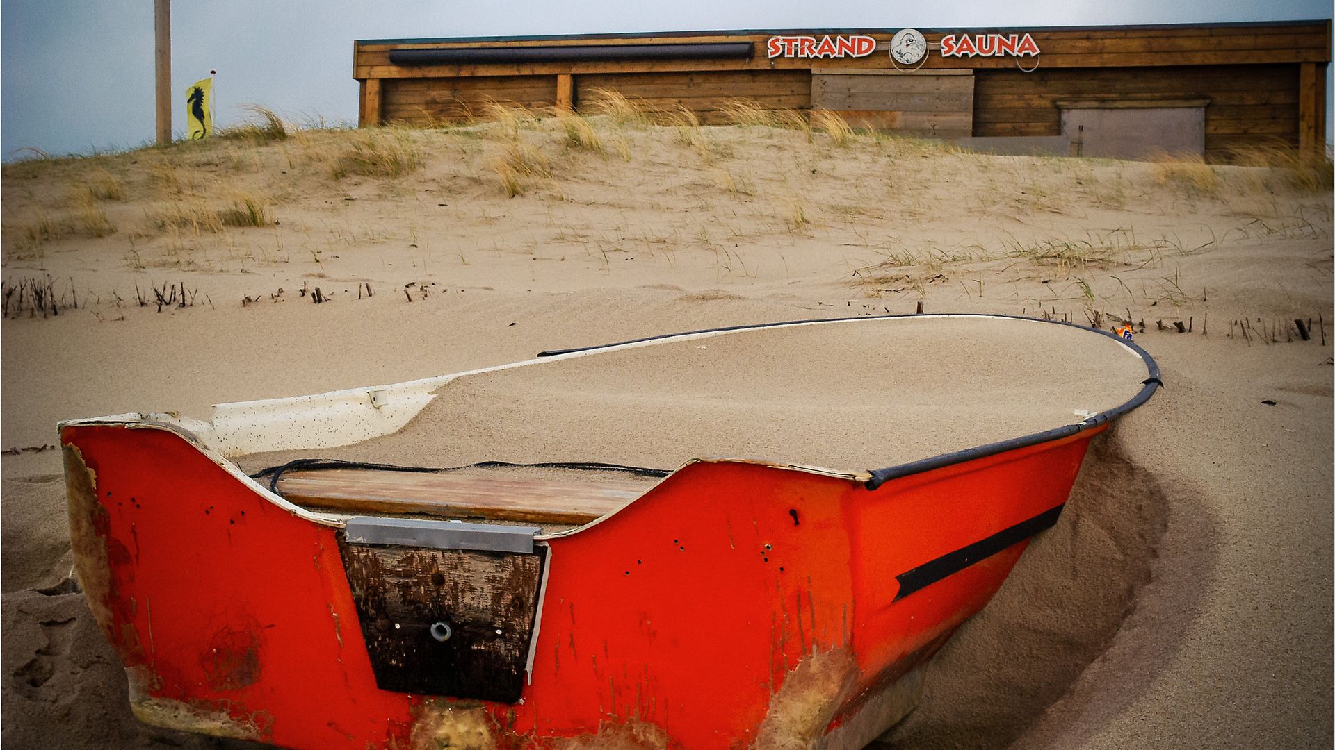 Rotes Ruderboot im Sand versunken